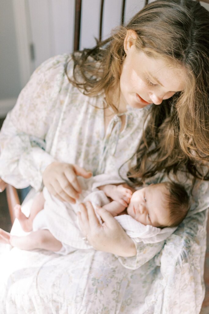 mom holding newborn baby in rocking chair