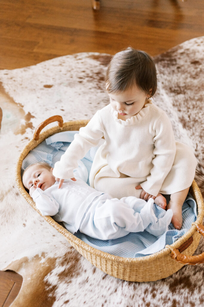 newborn baby with sister in moses basket