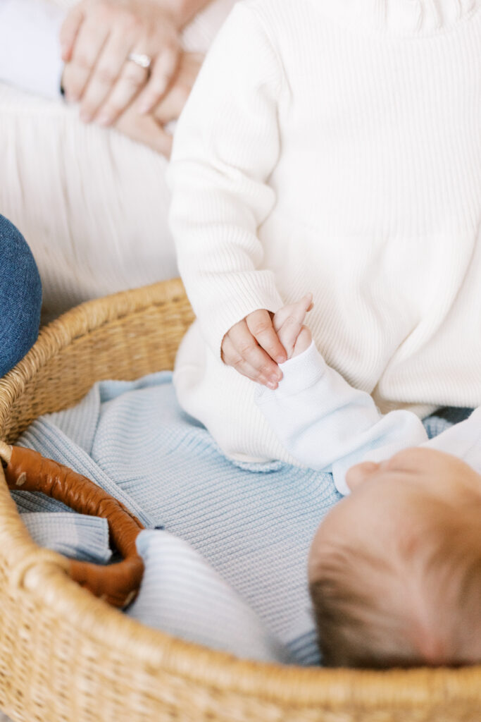 sister holding newborn baby's hand