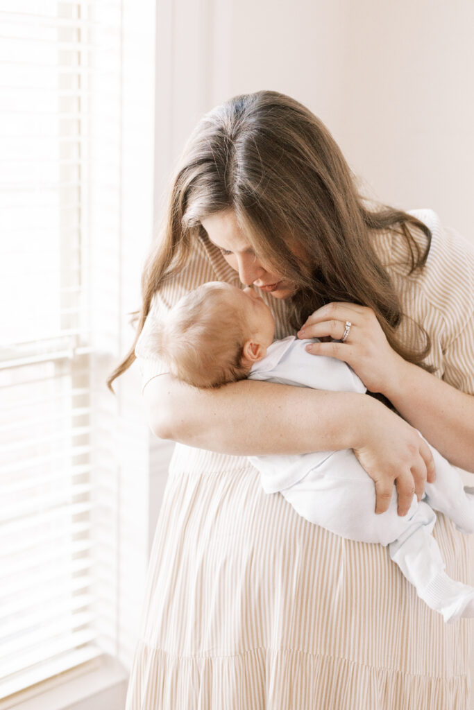 mom going nose to nose with newborn baby by window