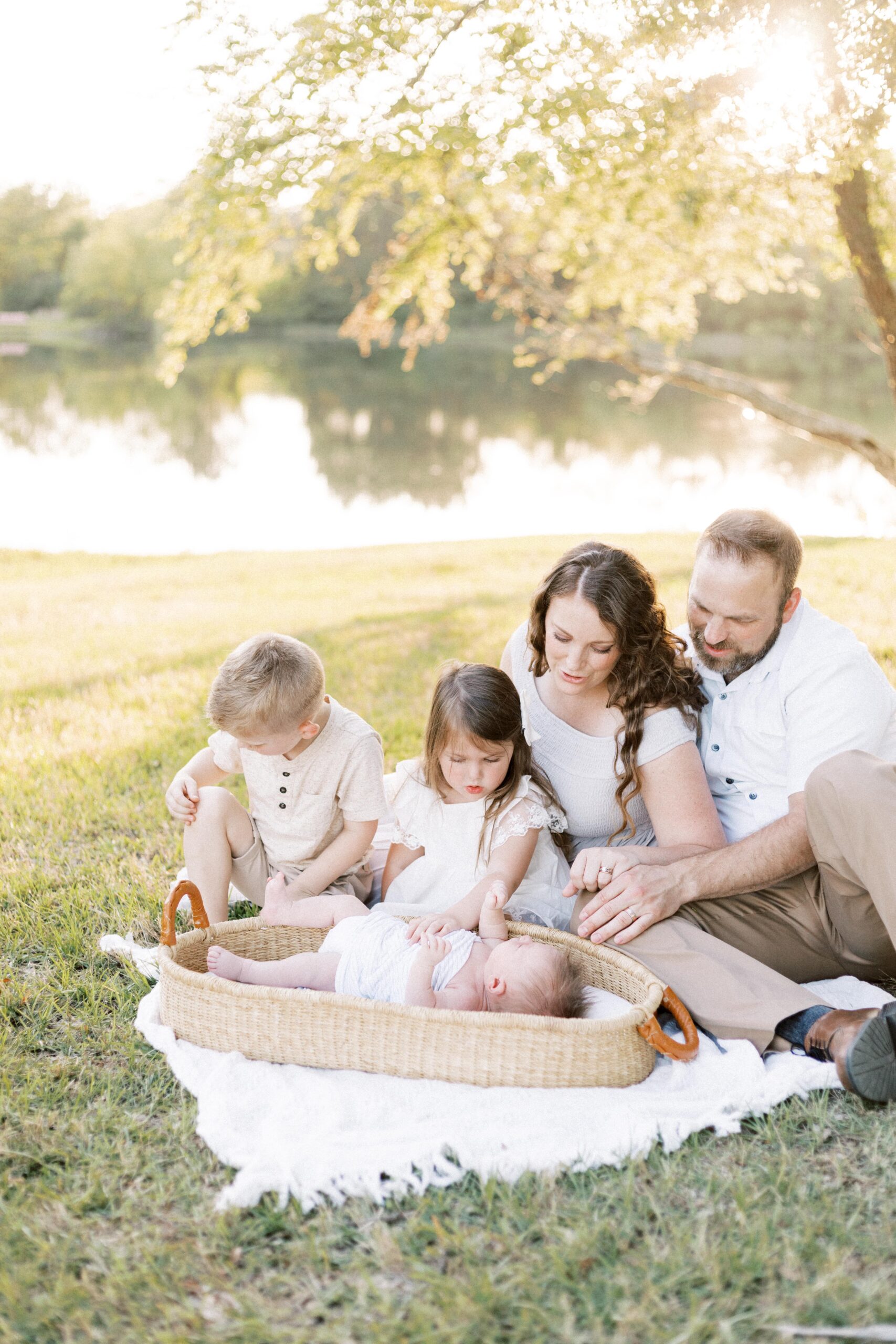 family admiring newborn baby in basket during peoria illinois outdoor newborn photos