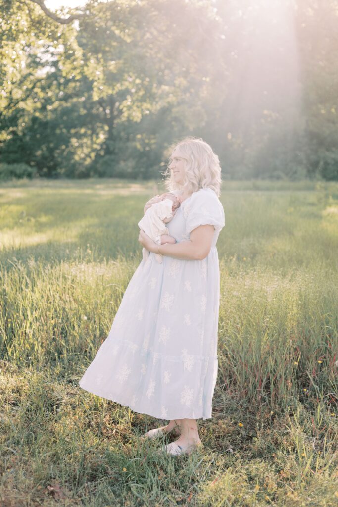 mom standing with baby in a field during peoria illinois newborn photos