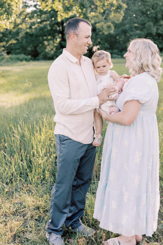 mom and dad looking at each other while holding children in newborn photos in peoria illinois