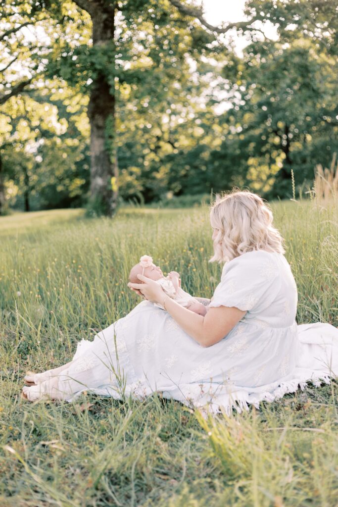 mom sitting in field with baby on lap in central illinois newborn photos