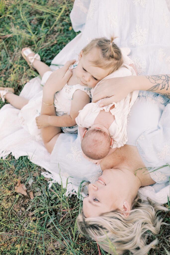 mom laying with babies in grass in central illinois newborn photos