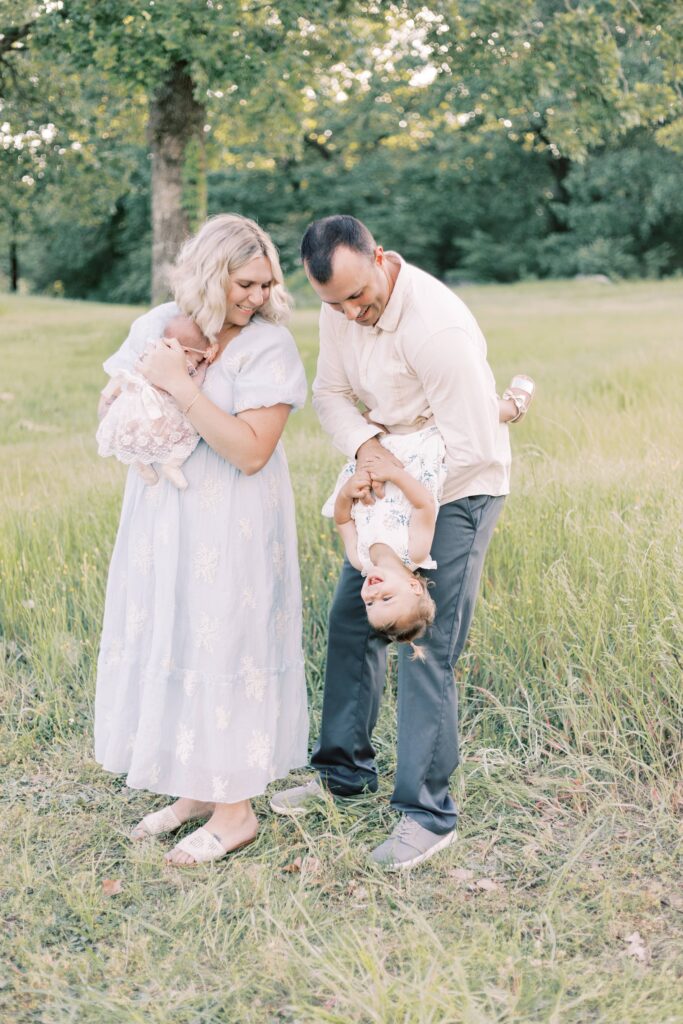 dad playing with daughter while mom holds baby in central illinois newborn photos