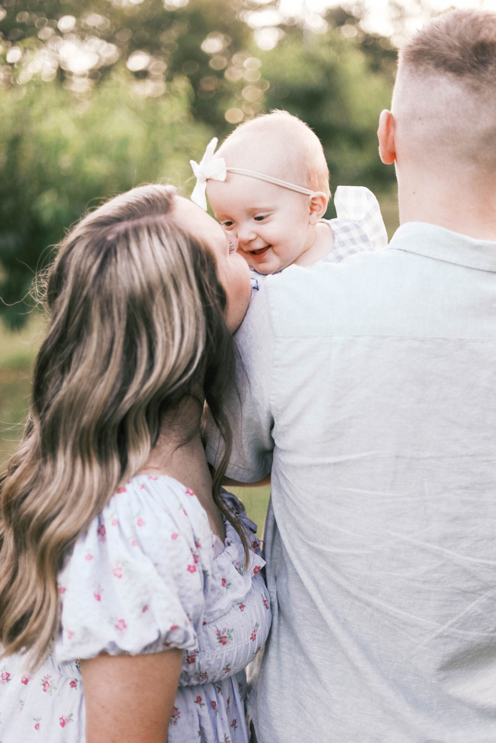 mom and baby giving butterfly kisses while dad is holding baby