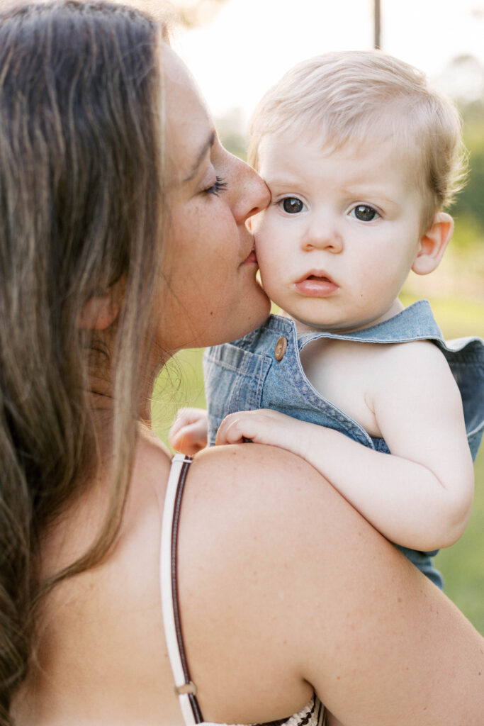 mom kissing baby on the cheek in sunset summer family photos