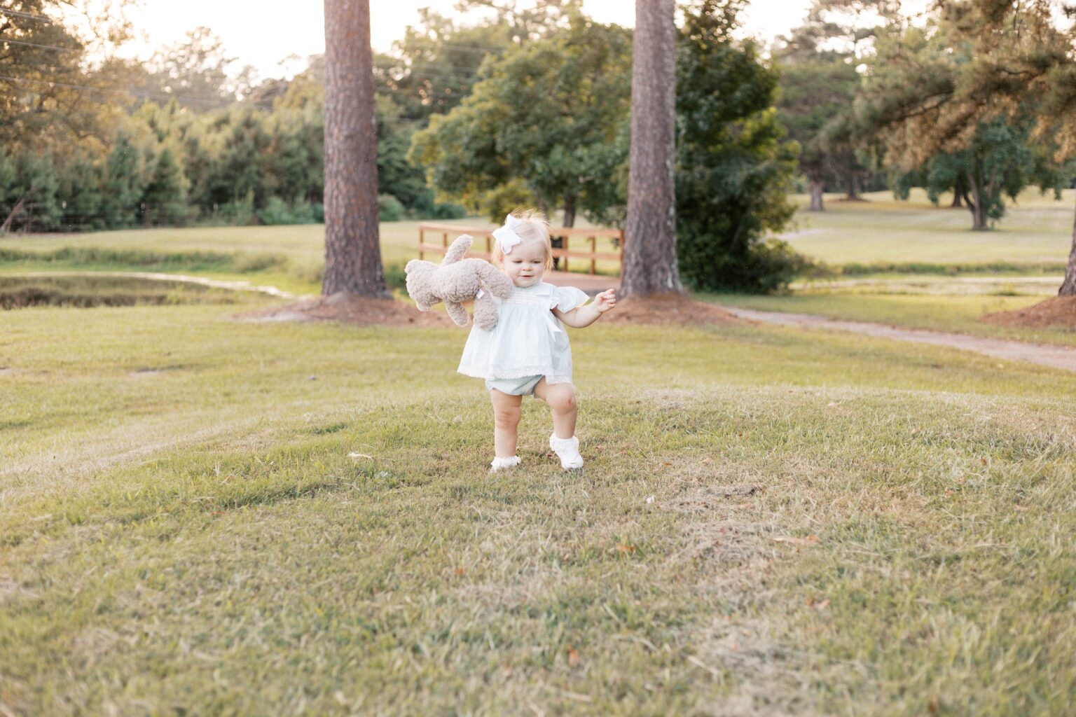 baby walking with stuffed animal during milestone photos