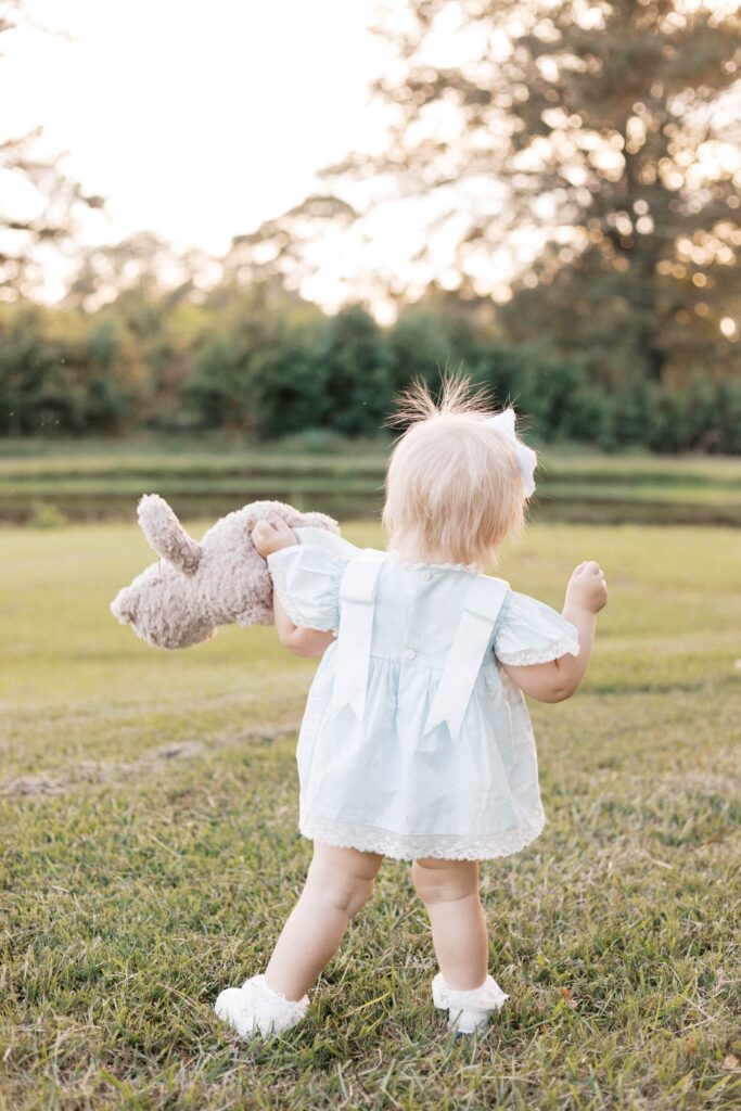 baby walking with stuffed animal during milestone photos