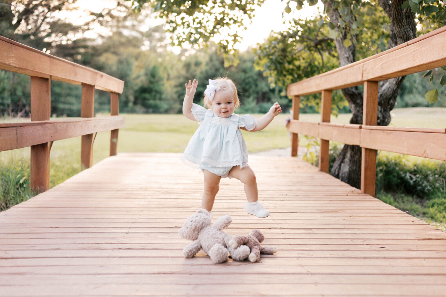 baby smiling on bridge with stuffed animal during one year milestone photos