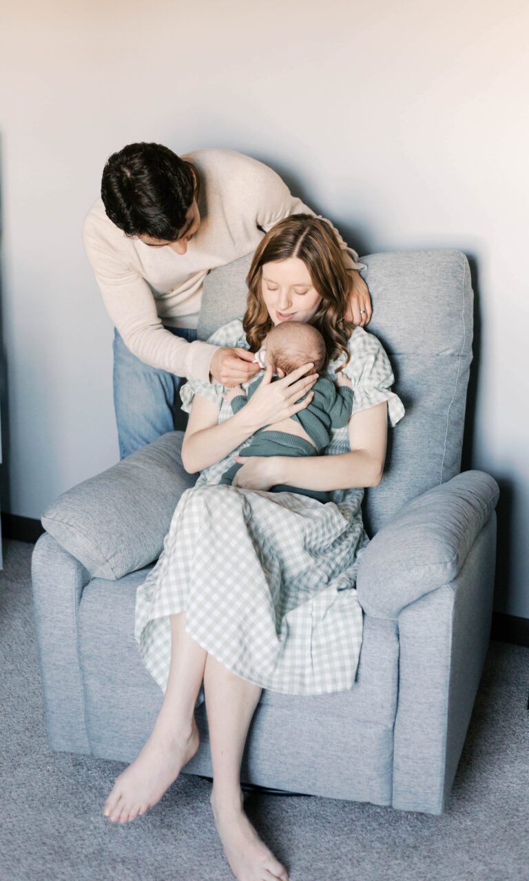 Cozy family snuggling with their newborn on a couch in a small Peoria apartment, showing how limited space still creates beautiful newborn photos.