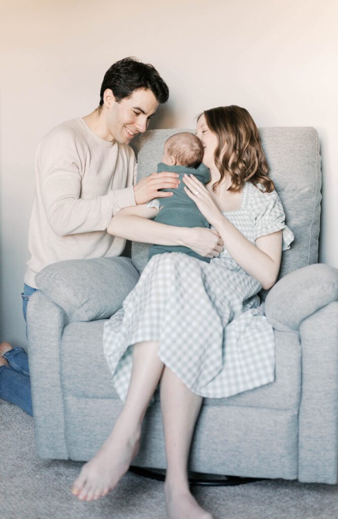 Cozy family snuggling with their newborn on a couch in a small Peoria apartment, showing how limited space still creates beautiful newborn photos.