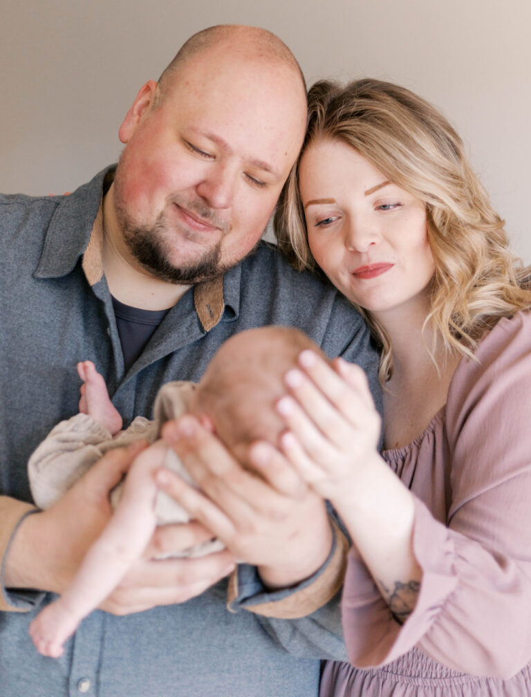 new parents looking at baby in living room during peoria il newborn photos