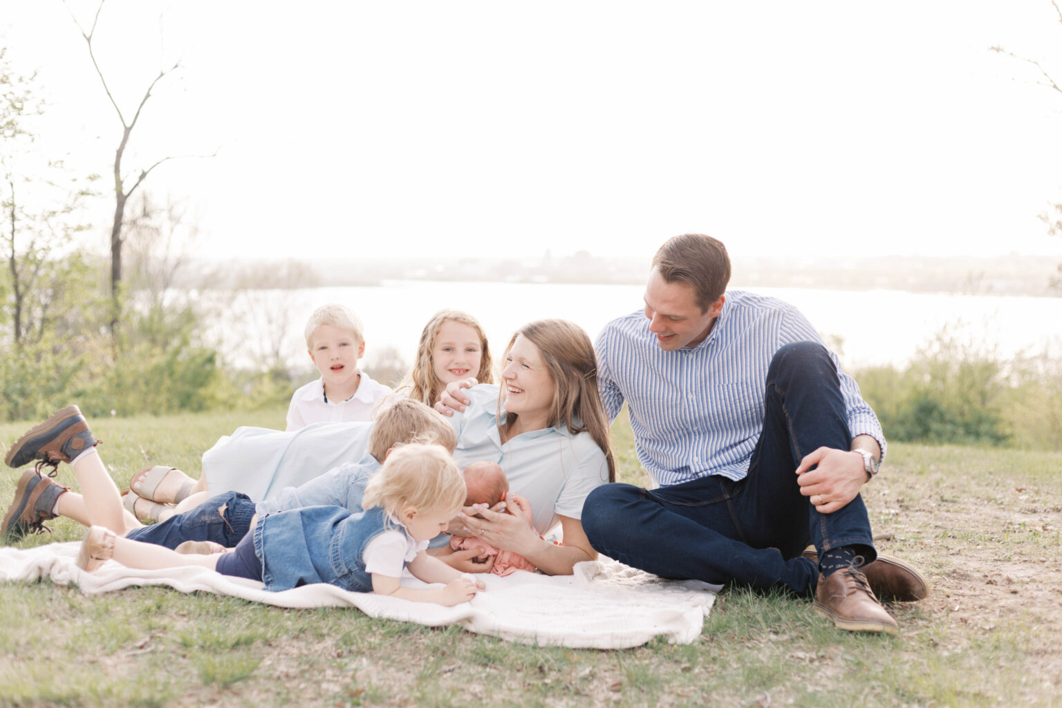 newborn photographer peoria il -77 family laughing on blanket during newborn photos overlooking the river in peoria il