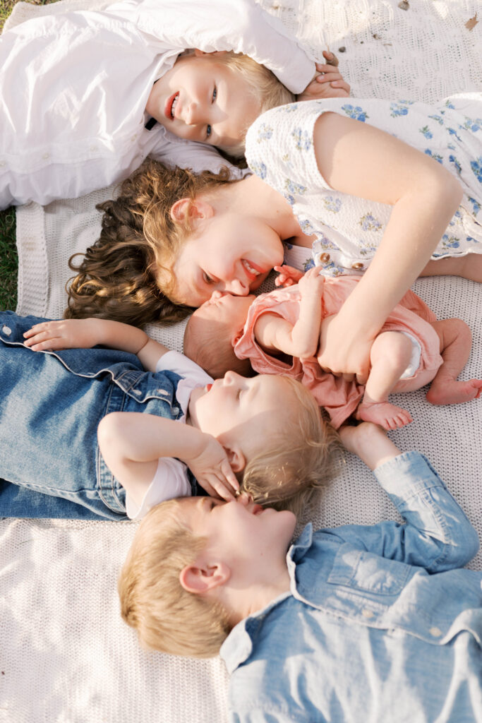 newborn photographer peoria il -93 siblings laying on blanket hugging newborn sister in peoria il newborn photos