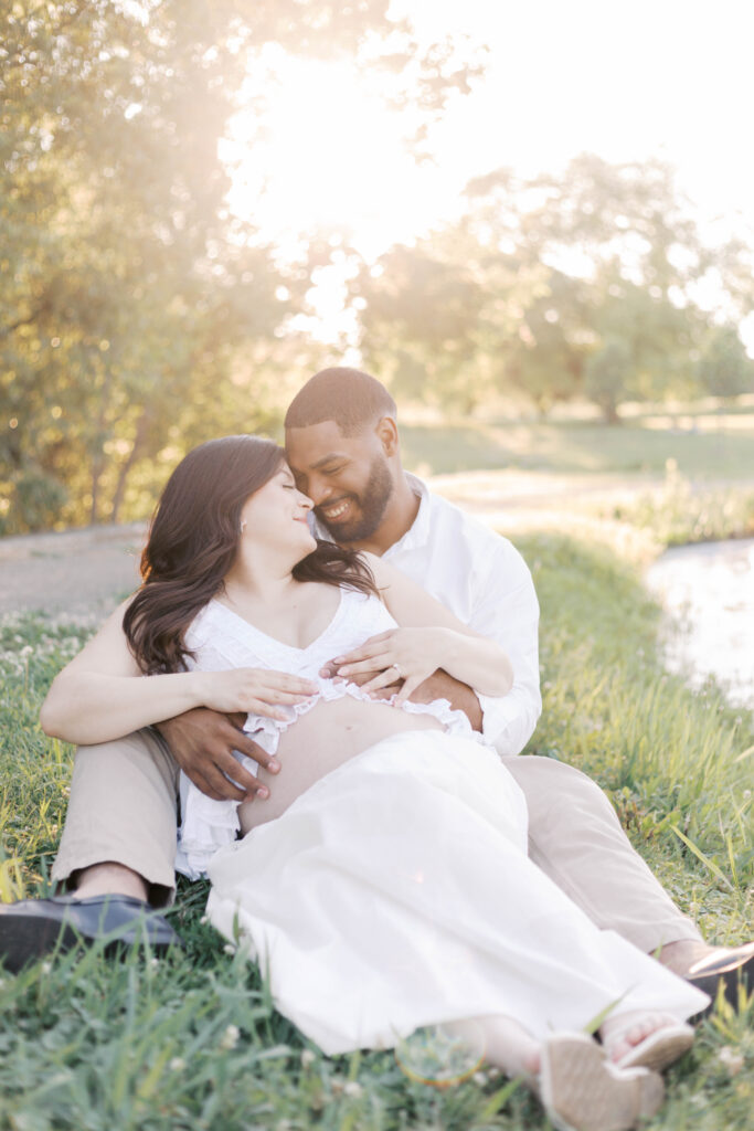 donovan park peoria il maternity photos-29 (1) couple sitting and smiling during golden hour maternity photos in peoria il