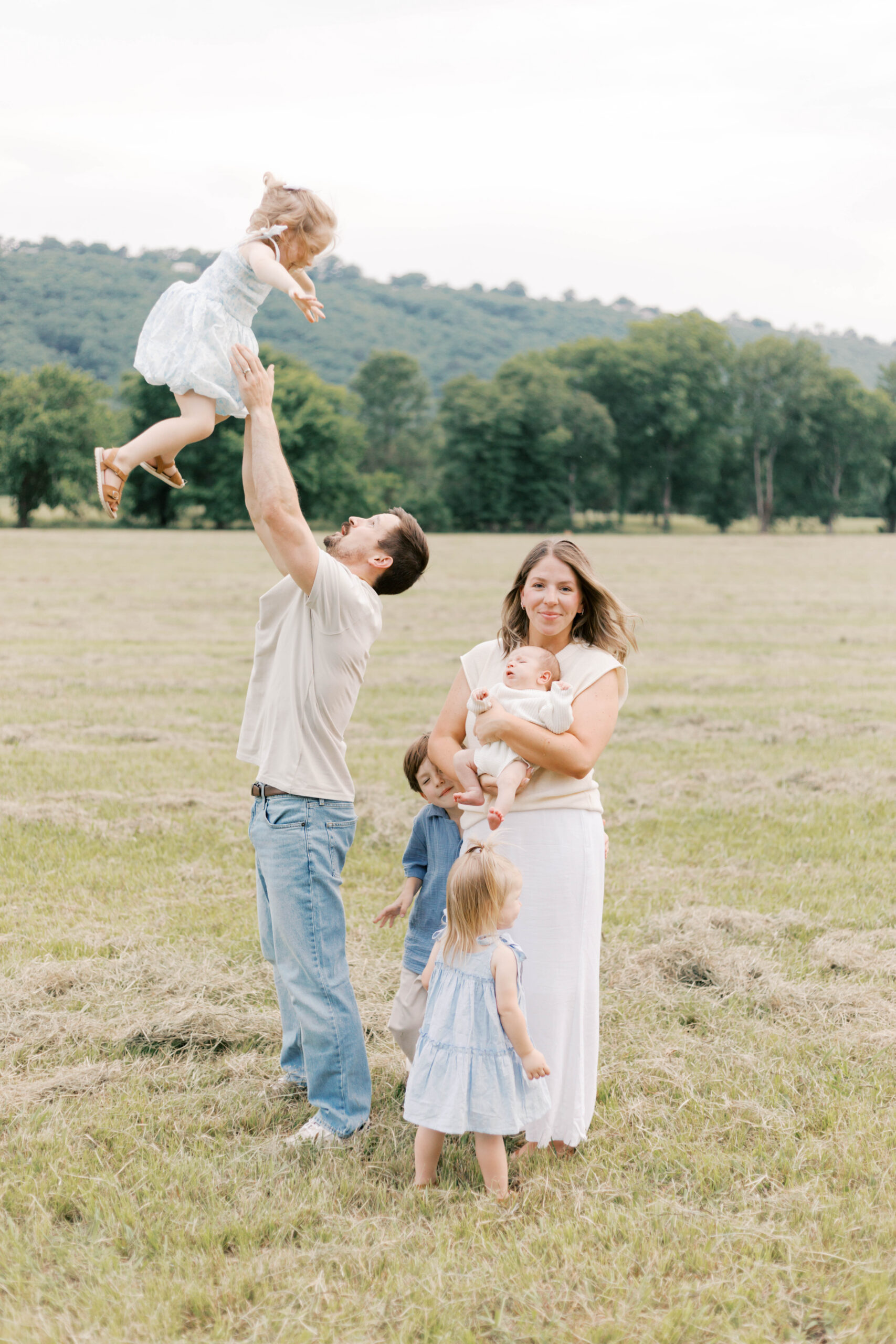 family with young children playing outside during newborn photos in peoria il