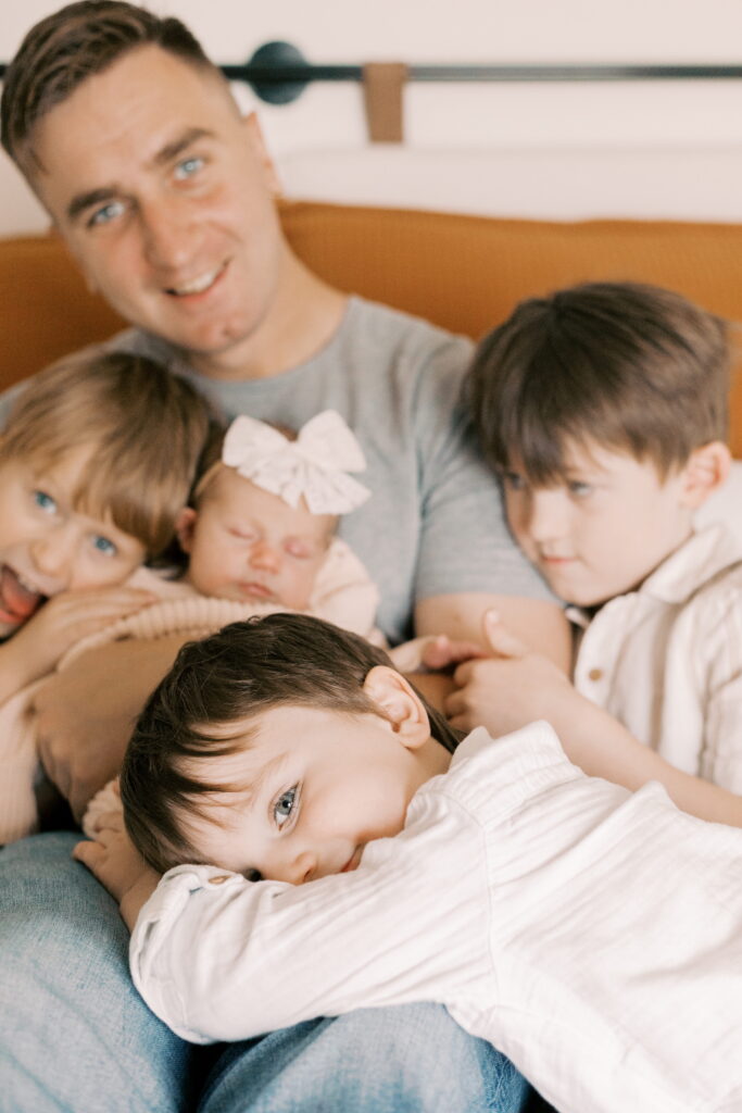 toddler lays on dad's lap in sibling newborn photos in peoria il