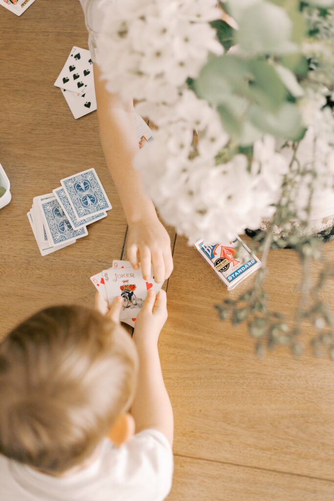 siblings playing card games at home during newborn photos in peoria il