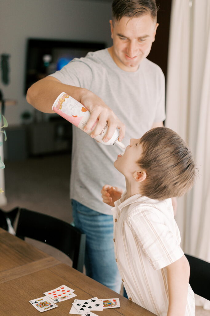 dad gives kids whipped cream during newborn photos in home in peoria il