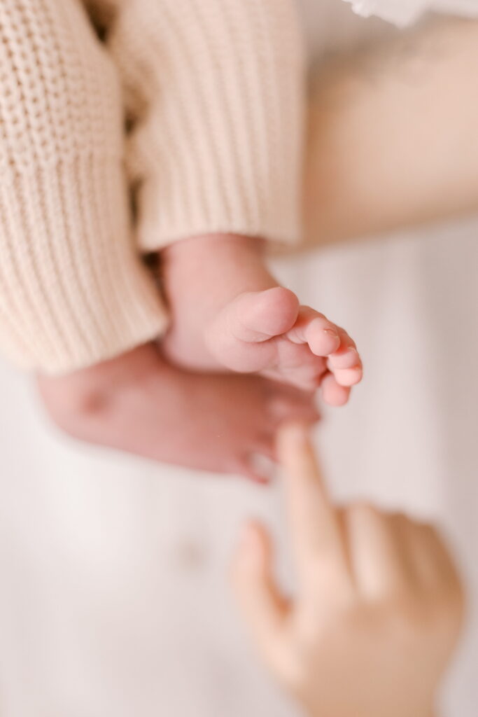 sibling touches baby toes in home newborn photography in peoria il