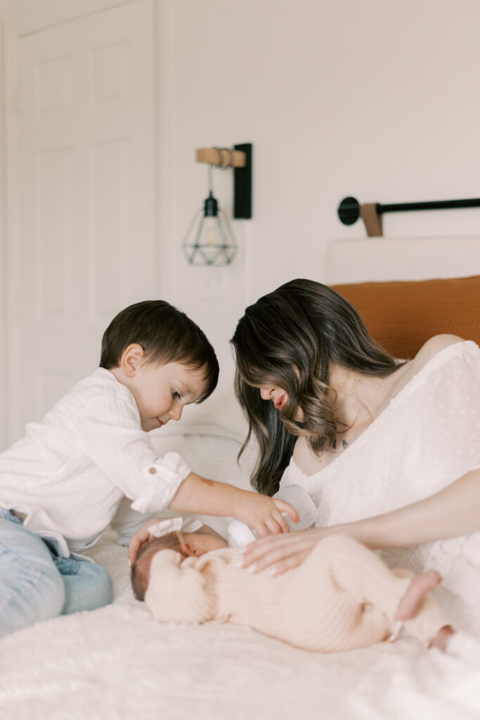 toddler feeds baby in newborn photograph peoria il